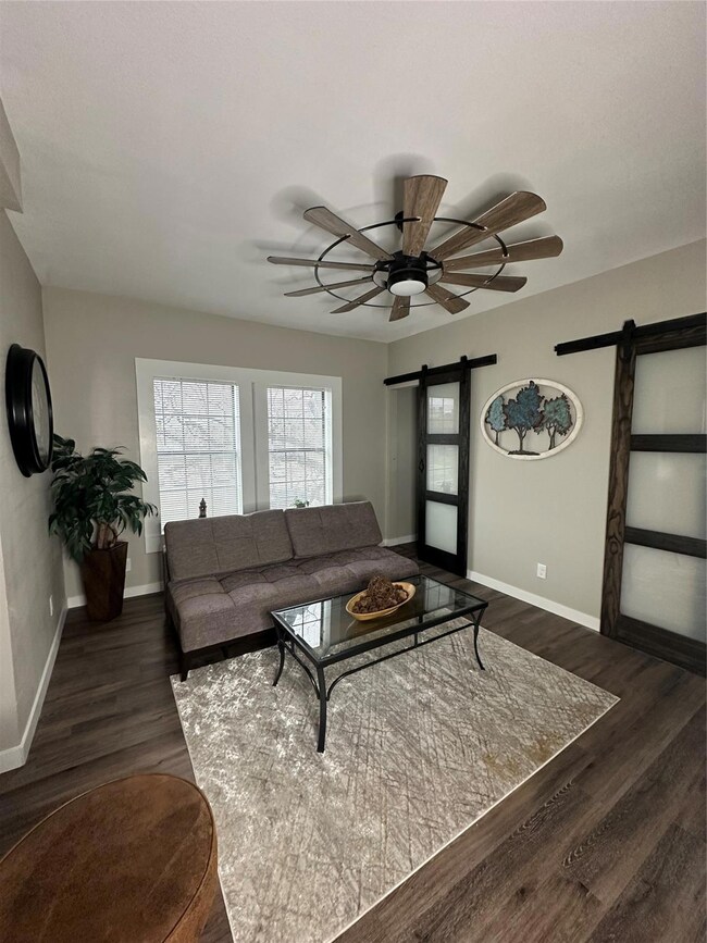Living room featuring a barn door, dark hardwood / wood-style floors, and ceiling fan
