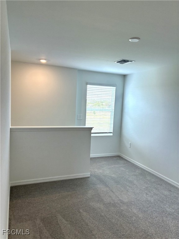 Unfurnished room featuring dark carpet and baseboards