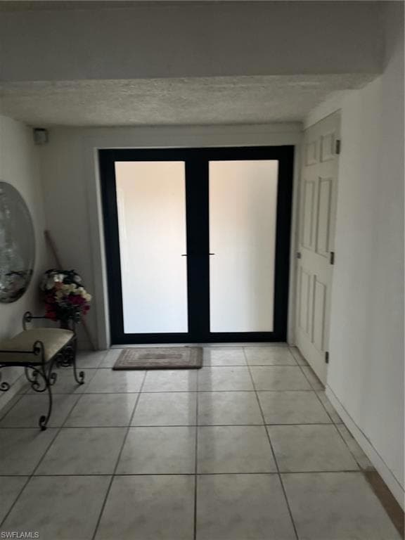 Doorway to outside with light tile patterned floors and a textured ceiling