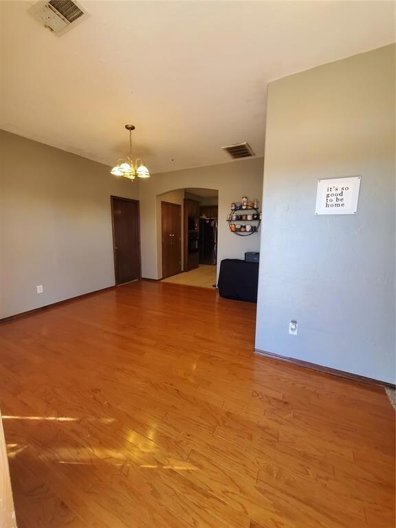 Unfurnished room with a chandelier and light wood-