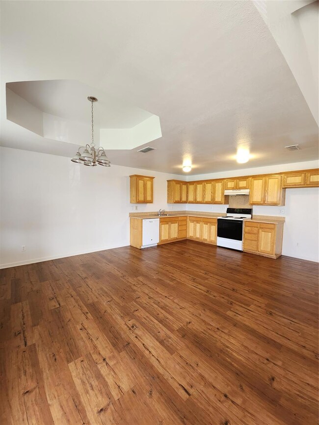 Kitchen with dark wood-style floors, range, light brown cabinets