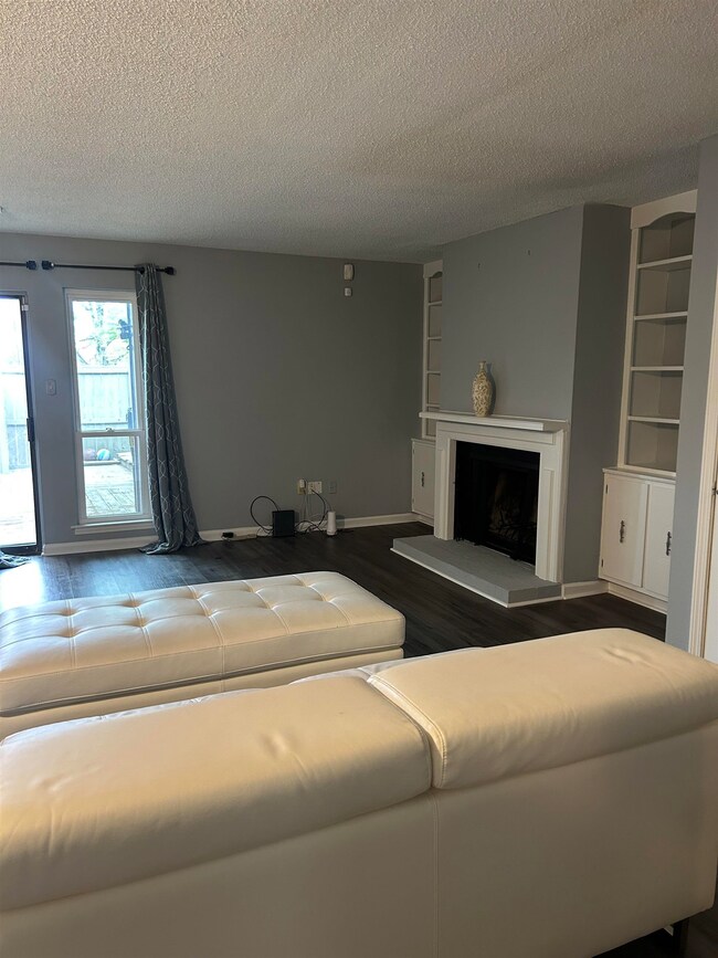Living room with a textured ceiling, a fireplace w