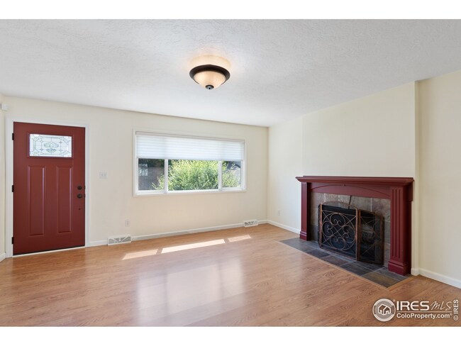 The main entrance leads into the living room with a striking fireplace focal point and laminate wood floors.