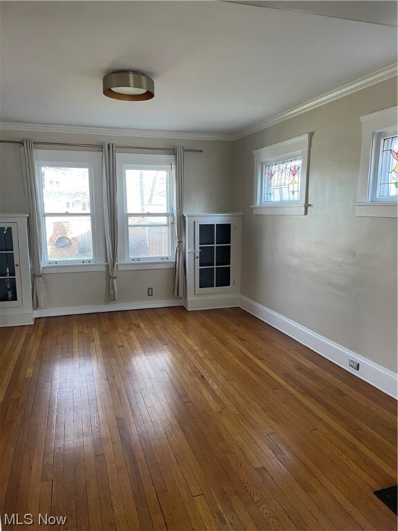 Dinning room featuring hardwood flooring, a healthy amount of sunlight, and ornamental molding