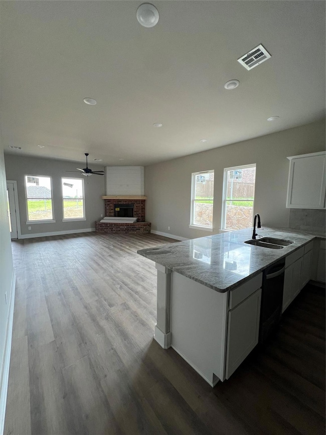 Kitchen with a sink, dishwasher, baseboards, a bri