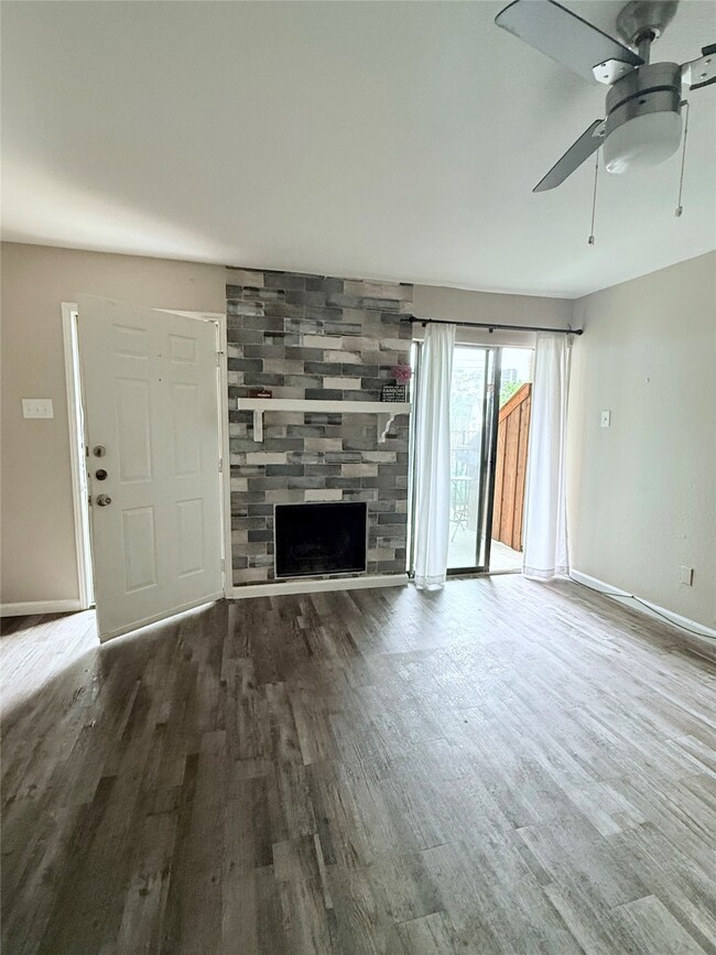 living room featuring a ceiling fan, a fireplace, and wood finished floors