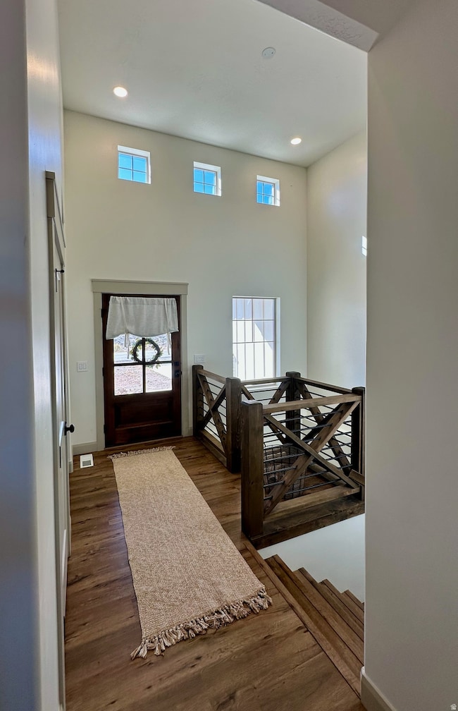 Entrance foyer with healthy amount of natural light, dark wood-style floors, recessed lighting, and a high ceiling
