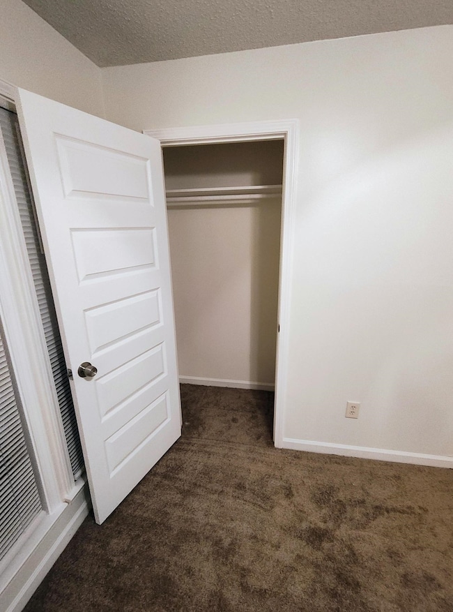 Unfurnished bedroom featuring dark colored carpet and baseboards
