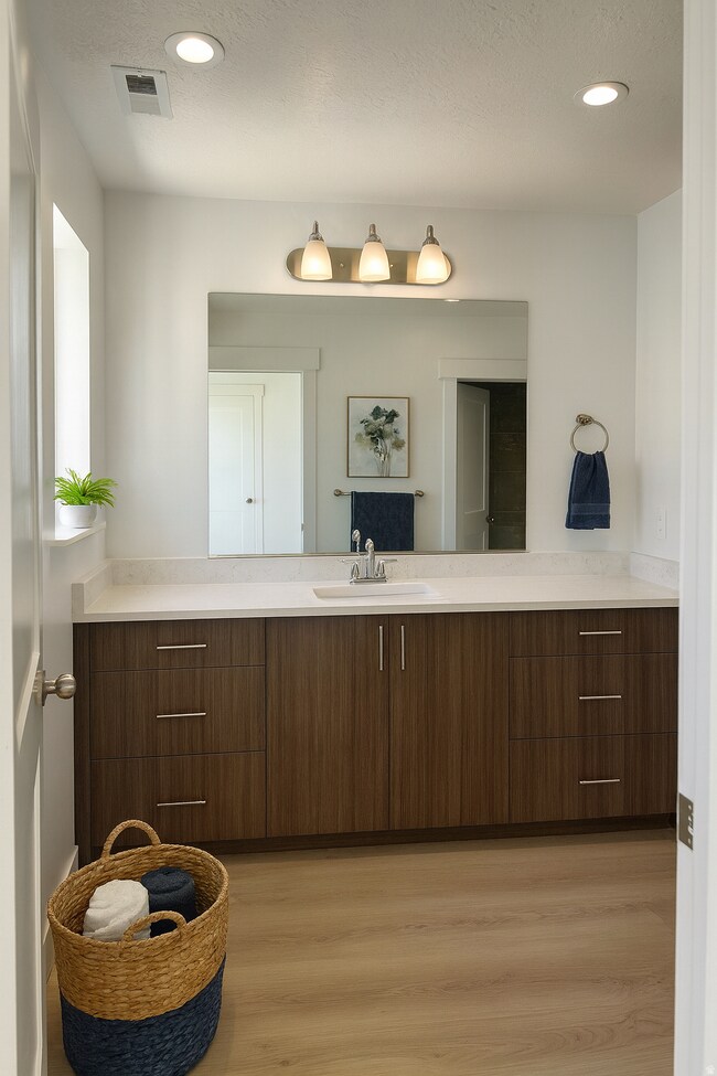 Half bath with vanity, light wood-style floors, a textured ceiling, and recessed lighting