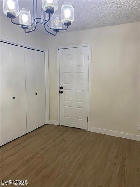 Foyer entrance with dark wood-style flooring, a textured ceiling, and a chandelier