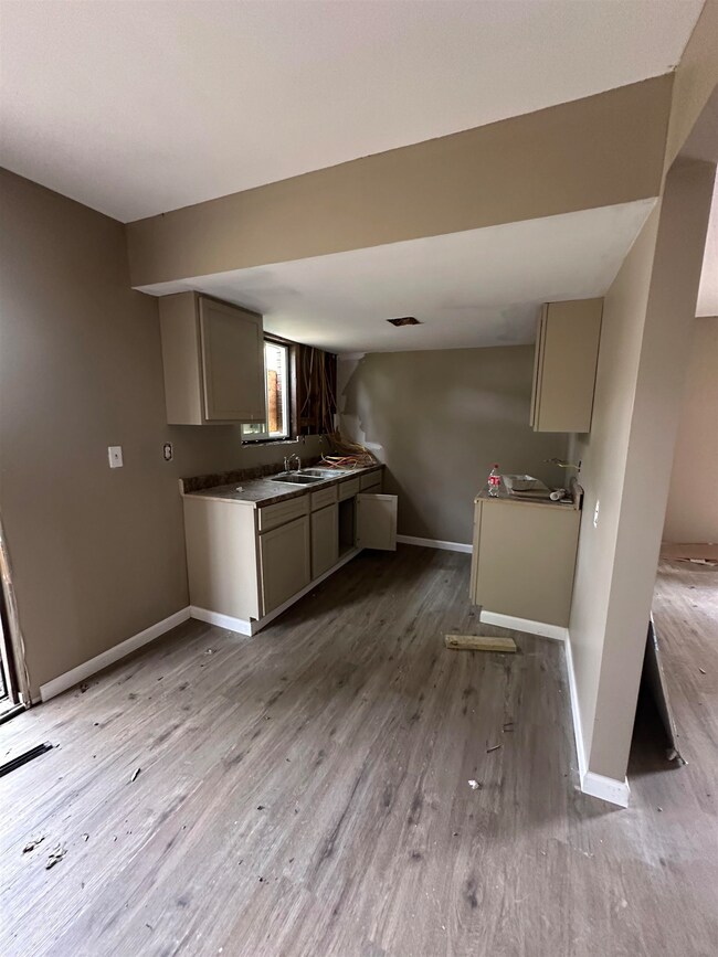 Kitchen featuring light wood-type flooring, baseboards, gray cabinetry, visible vents, and a sink