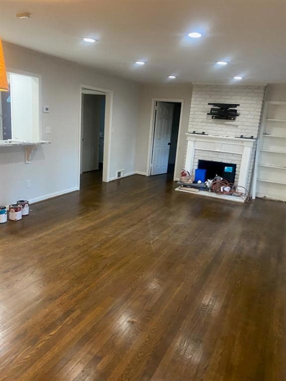 Unfurnished living room with dark wood-type flooring, a fireplace, baseboards, and recessed lighting