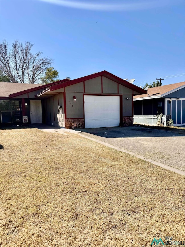 View of front of house featuring driveway, stone siding, a garage, and a front lawn