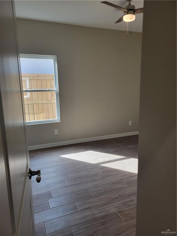 Spare room featuring dark wood-type flooring and ceiling fan