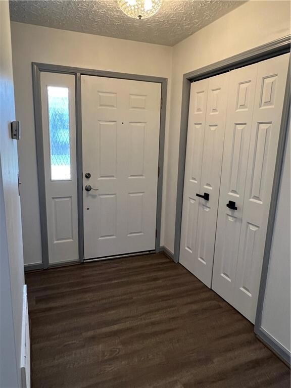 Entryway featuring dark wood-style flooring, a textured ceiling, and baseboards