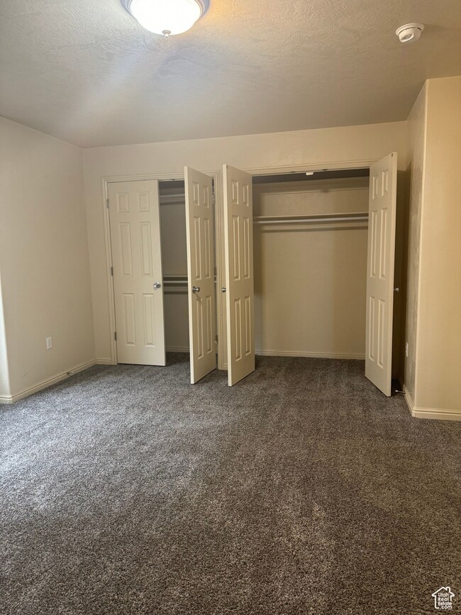 Unfurnished bedroom with dark carpet and multiple closets