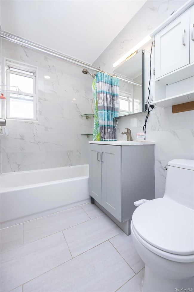 Bathroom with vanity, shower / bathtub combination with curtain, plenty of natural light, and light tile patterned floors