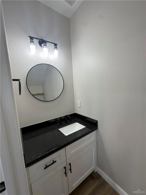 Bathroom featuring wood finished floors, vanity, and baseboards