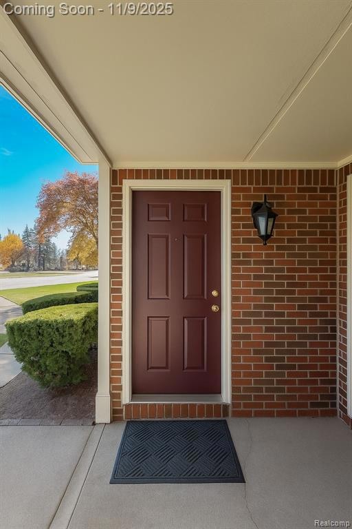 Property entrance featuring a porch and brick siding