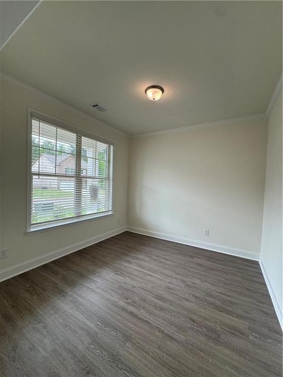 Empty room featuring crown molding and dark wood-type flooring
