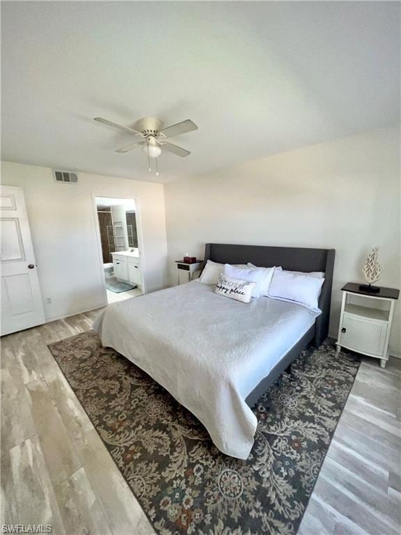 Bedroom with wood finished floors, a ceiling fan, and connected bathroom
