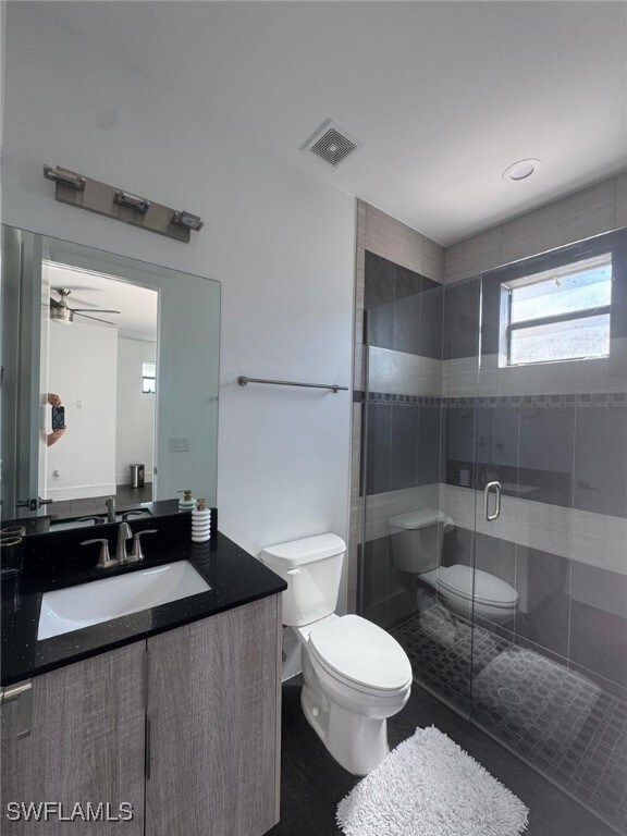 Bathroom featuring toilet, ceiling fan, visible ve