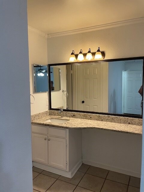 Bathroom with ornamental molding, light tile patterned floors, and vanity