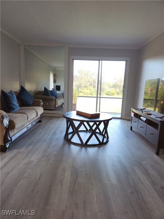 Living room with ornamental molding and wood finished floors