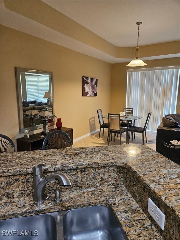 Kitchen with dark stone countertops, pendant lighting, and light tile patterned flooring