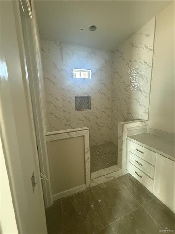 Bathroom featuring a marble finish shower and vanity