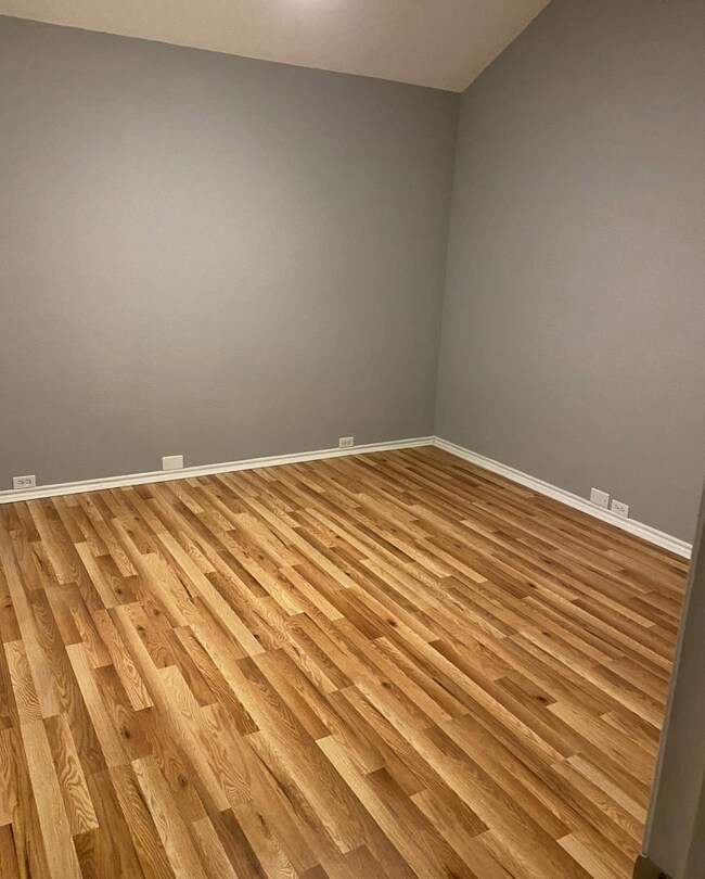 Unfurnished room featuring light wood-type flooring and lofted ceiling