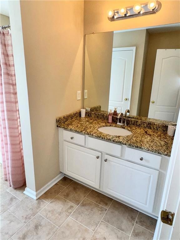 Full bath with vanity, baseboards, and tile patter