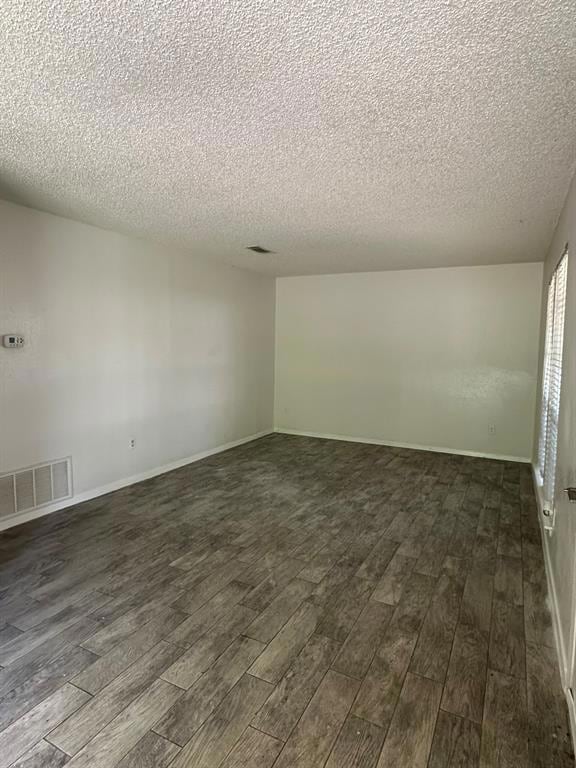 Spare room with a textured ceiling and dark wood-style flooring