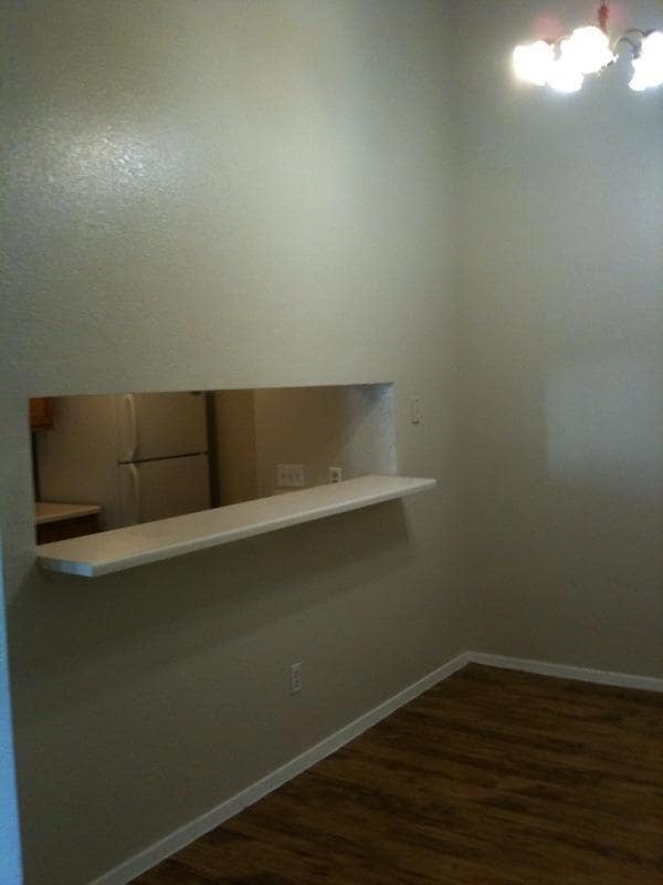 Spare room featuring baseboards and dark wood fin