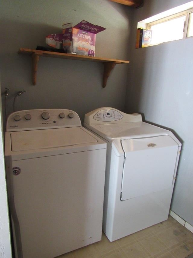 Clothes washing area featuring light tile patterned floors and washer and clothes dryer