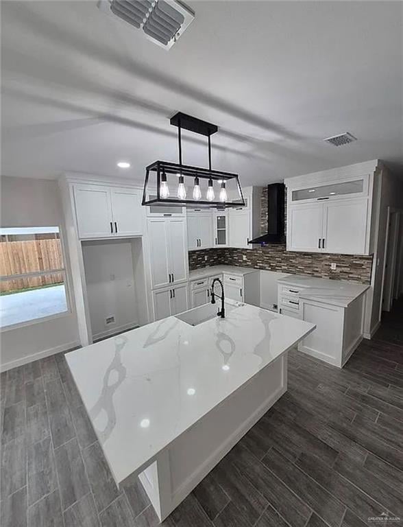 Kitchen featuring white cabinets, decorative backsplash, light stone counters, wood finish floors, and recessed lighting