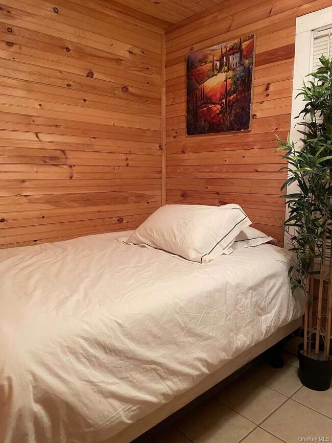 Bedroom with wood walls, light tile patterned flooring, and wood ceiling