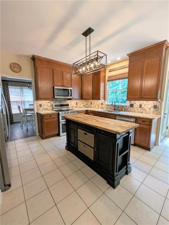 Kitchen with appliances with stainless steel finishes, wooden counters, backsplash, and light tile patterned flooring looking into the dining room