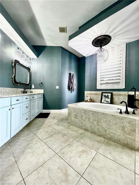 Bathroom featuring a bath, vanity, and tile patterned floors