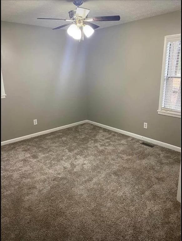 Empty room with ceiling fan, carpet flooring, and baseboards