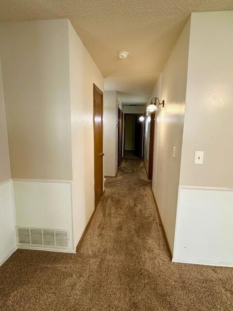 Hallway featuring carpet and a textured ceiling
