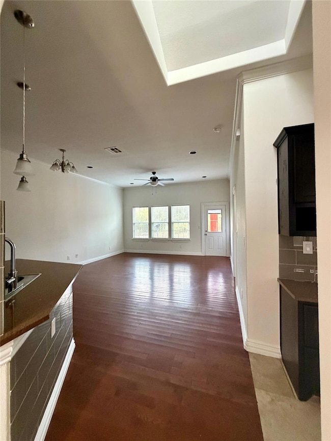 Unfurnished living room featuring dark wood-style flooring and baseboards