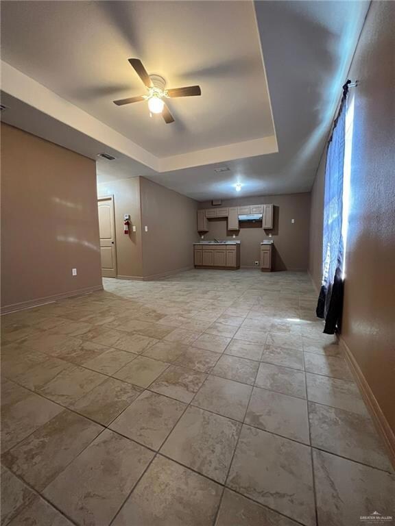 Unfurnished room featuring a raised ceiling and ceiling fan