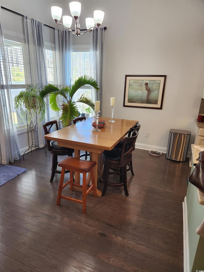 Dining area with dark wood-style floors and a chandelier