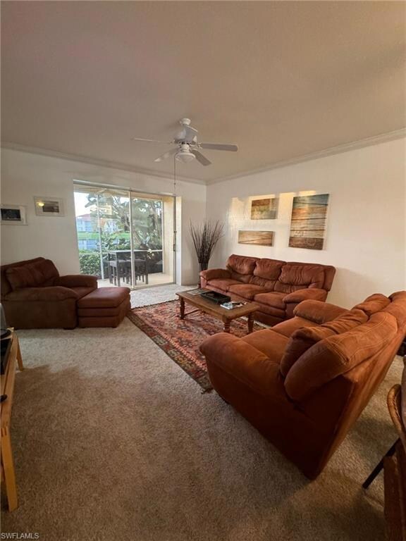 Carpeted living room with ornamental molding and c