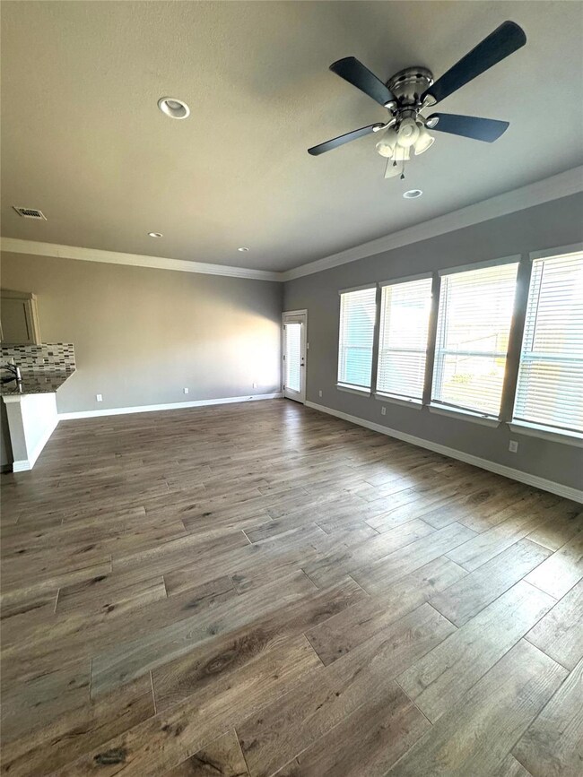 Unfurnished living room featuring crown molding, dark wood-style floors, a ceiling fan, and recessed lighting