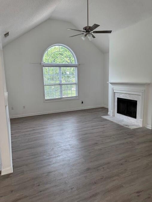 Spacious living room featuring new ceiling fan, a high end fireplace, lofted ceiling, dark wood-style flooring, and baseboards