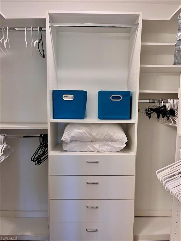 Large walk in closet with shelving, drawers, short and long hanging areas