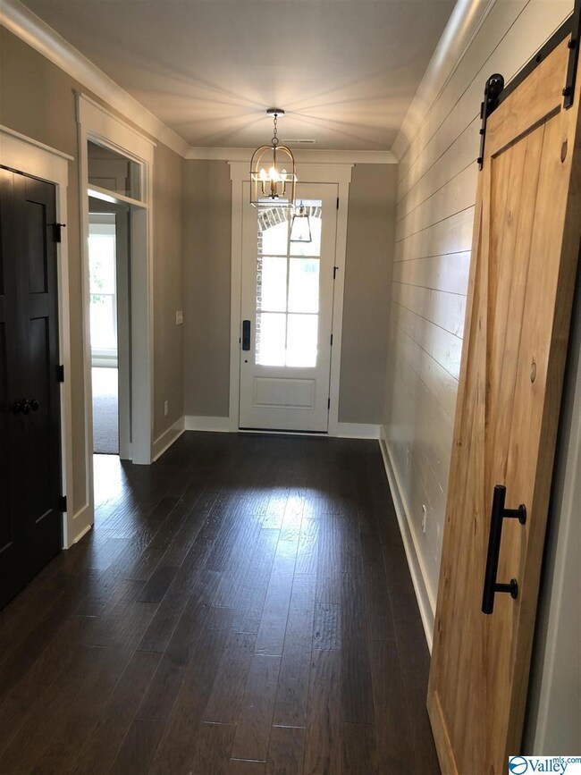 The open and airy welcome room has a half bath, a privacy foyer to the secondary bedrooms, and a barn door to the utility hallway leading to the tandem garage.