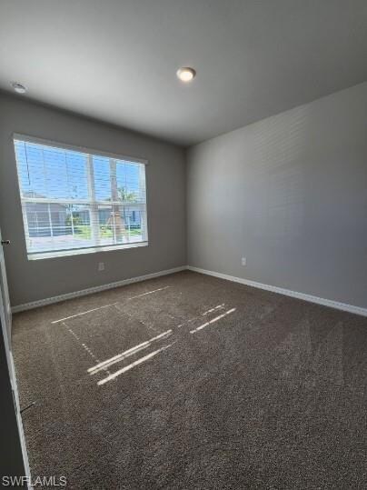 Empty room featuring baseboards and carpet
